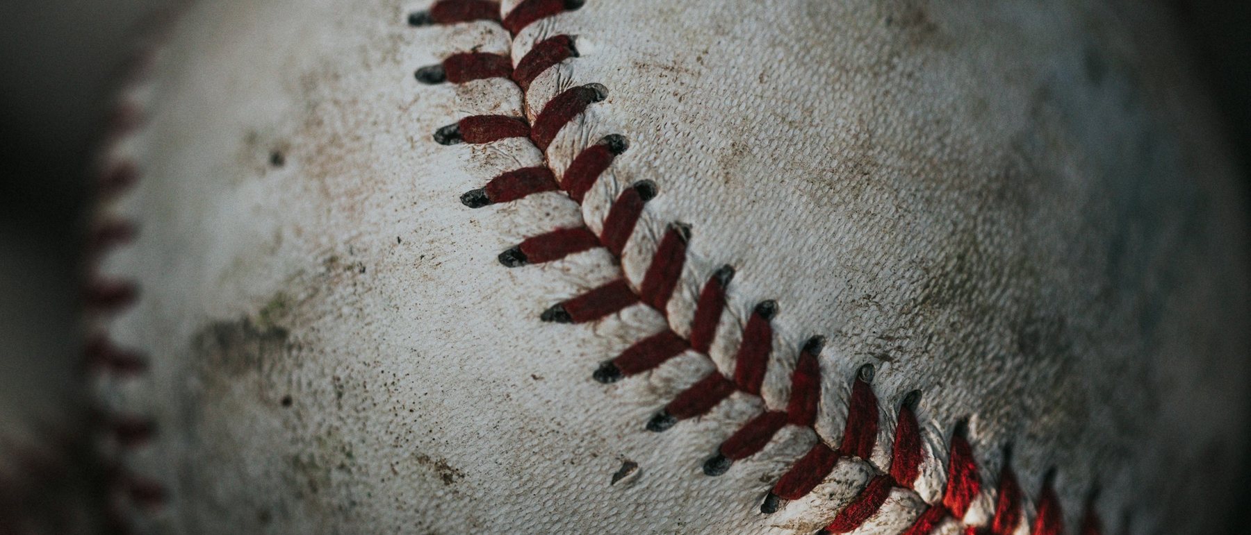 A young baseball player standing on an infield, seen from the waist down, glove at his side.